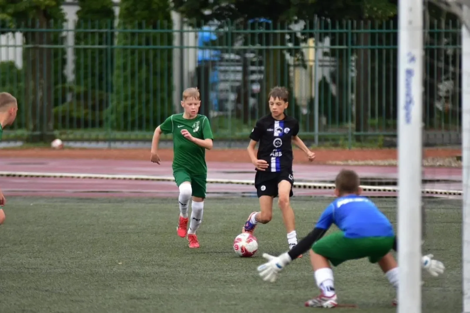 Zawodnik w zielonym stroju prowadzi piłkę w stronę bramkarza podczas sparingu rocznika 2014.