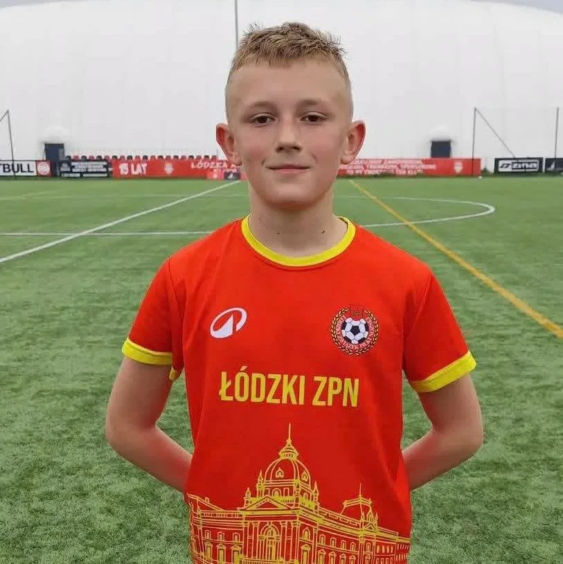 Kacper Mąkol w czerwonej koszulce Łódzkiego ZPN na boisku.