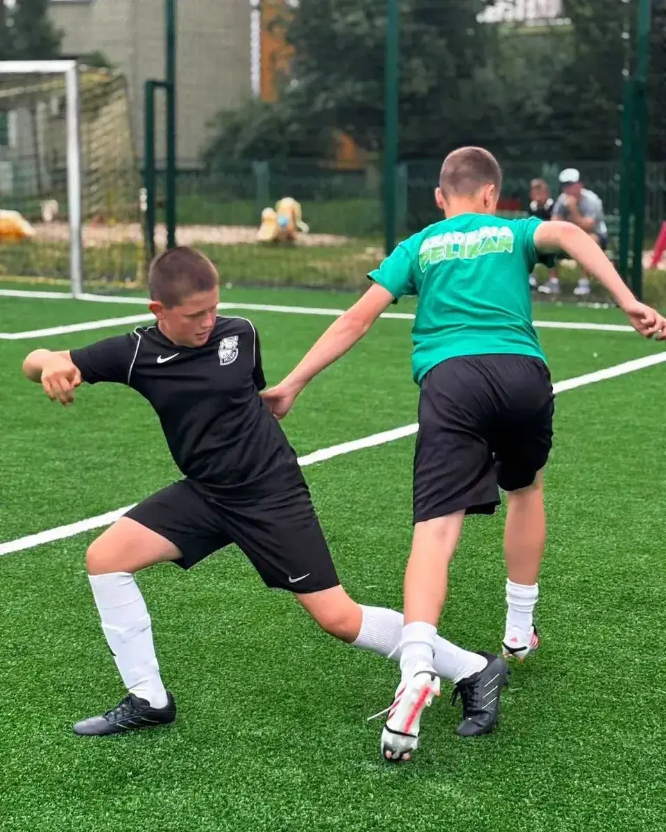 Dwaj młodzi piłkarze walczą o piłkę na boisku podczas turnieju Zatorze Cup.