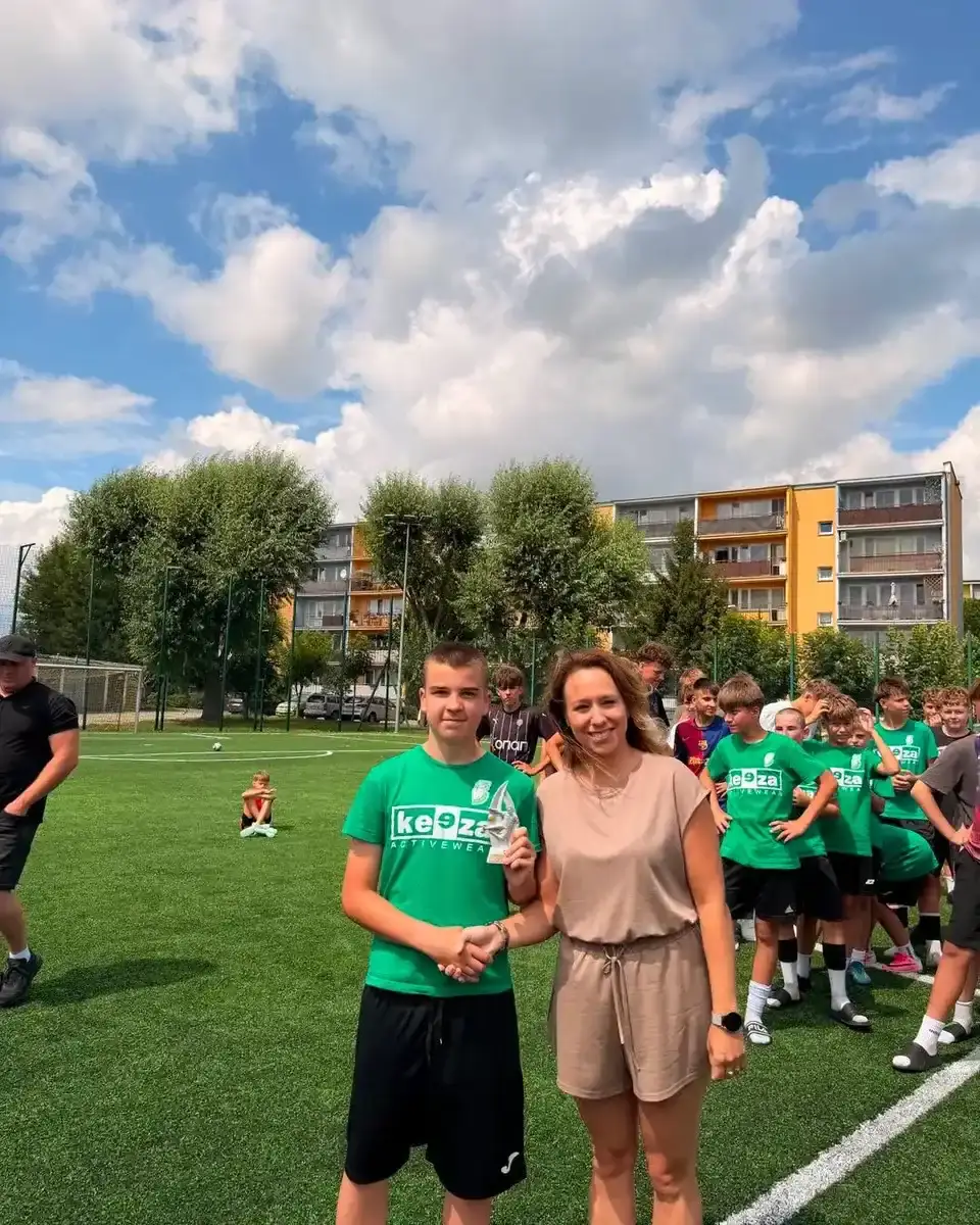 Zawodnik w zielonej koszulce prezentuje trofeum obok kobiety podczas turnieju Zatorze Cup.